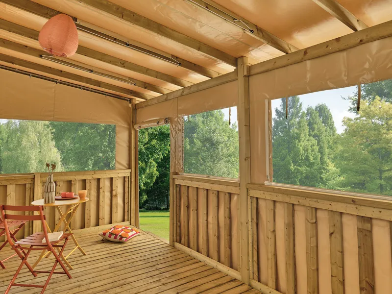 Vue intérieure d’une terrasse Clairval équipée de toiles de côtés et façade sur système coulissant